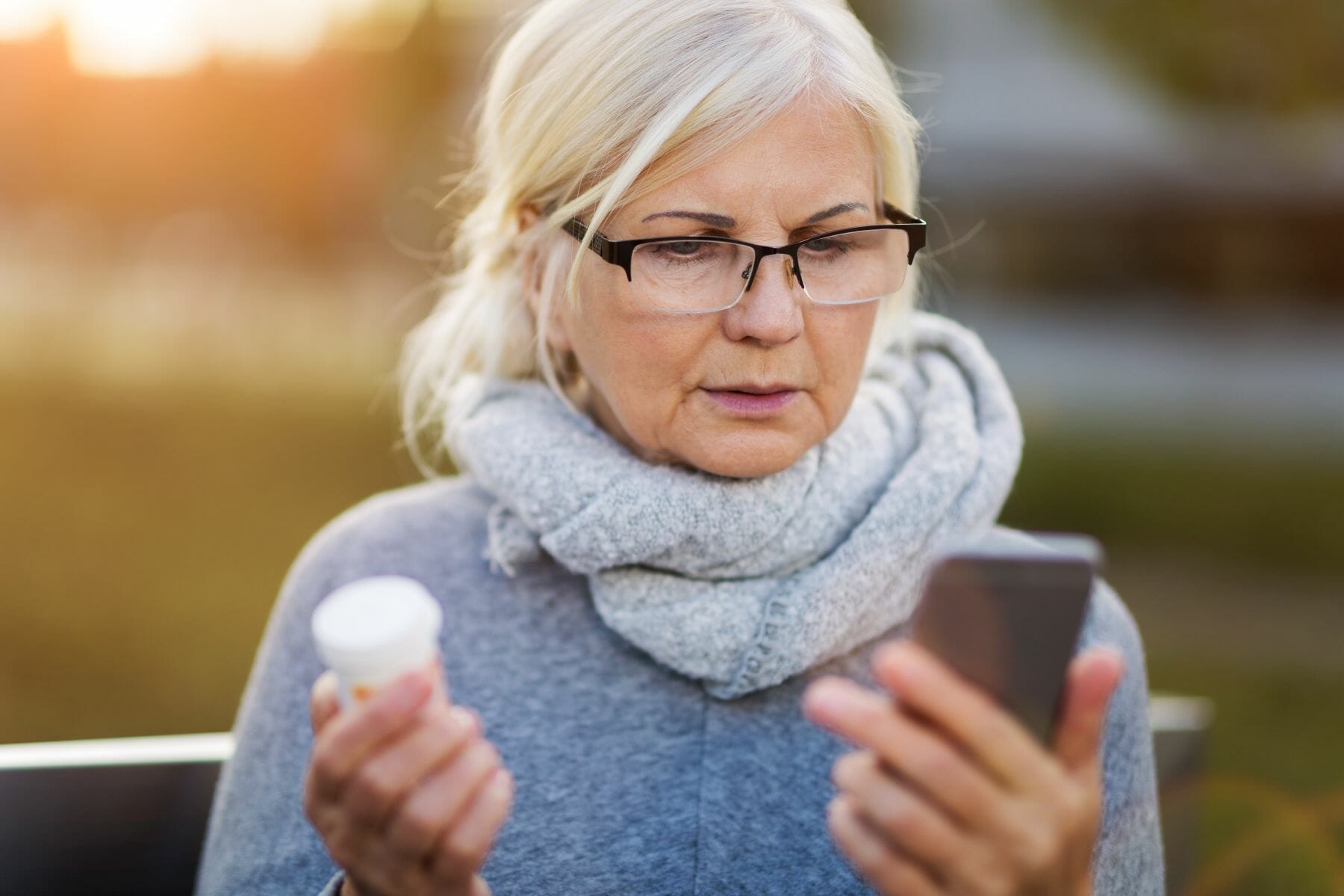 Woman holding smartphone and pill bottle Woman holding smartphone and pill bottle